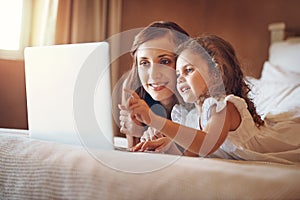 Technology both educates and entertains. a mother and her little daughter using a laptop together at home.