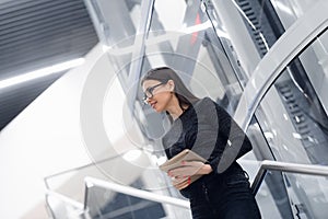 Technology, business and corporate concept - happy woman or student with tablet pc computer standing on stairs at modern