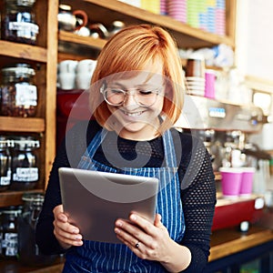 Technology can be used to assist and expand your business. a young woman using a digital tablet while working in a