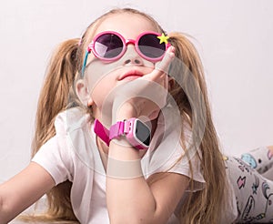 Technology for children: a girl wearing pink glasses uses a smartwatch