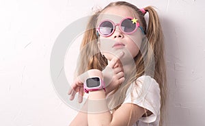 Technology for children: a girl wearing pink glasses uses a smartwatch.