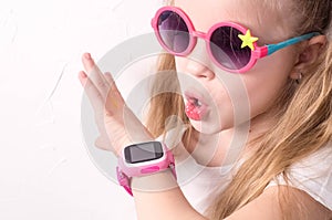 Technology for children: a girl wearing pink glasses uses a smartwatch.