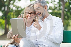 Technology connect and modern lifestyles concept. Aged senior couple waving hands greeting grandkids via facetime video