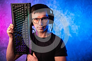 Technology, cyberspace, programming and people concept - hacker man in headset and eyeglasses with keyboard over neon