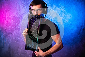 Technology, cyberspace, programming and people concept - hacker man in headset and eyeglasses with keyboard over neon