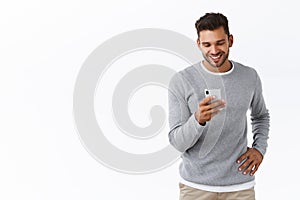 Technology, futuristic concept. Handsome carefree modern guy chatting with friends via smartphone messanger, holding photo