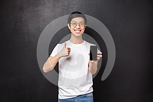 Technology, gadgets and people concept. Assertive cute asian guy in t-shirt and glasses, recommend online store or