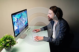 Technology, gaming, let`s play and people concept. Young man or hacker in headset and eyeglasses with pc computer playing game an