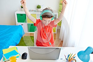 Boy with headphones playing video game on laptop