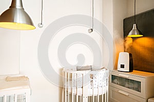 Technology and health. Steam Humidifier in the children bedroom next to the newborn baby bed in a stylish light interior with a wa