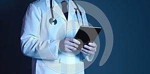 Technology in healthcare: doctor\'s digital tablet, blue background, face concealed.