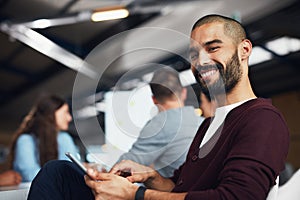 Technology helps me get more work done in the day. Portrait of a young man sitting at a table in an office using a