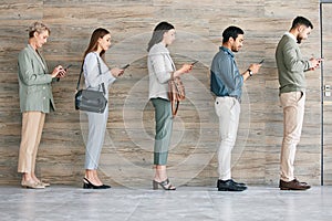 Technology helps with the wait. Full length shot of a diverse group of businesspeople standing in a line together and