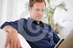 Technology at home. a handsome man using his tablet while sitting on the sofa at home.