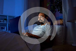 indian man with laptop in bed at home at night