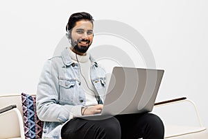 technology, leisure and people concept - happy man in wireless headphones with laptop at home