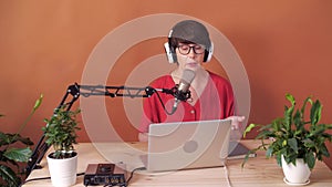 Technology and mass media concept. Middle-aged woman with microphone and laptop computer talking and recording podcast