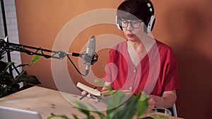 Technology and mass media concept. Middle-aged woman with microphone and laptop computer talking and recording podcast
