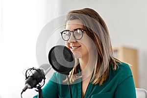 Woman with microphone recording podcast at studio