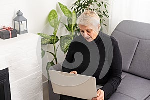 technology, old age and people concept - happy senior woman in glasses with laptop computer at home