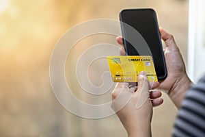 Technology, online shopping and e-Commerce concept. Close up of woman hand holding credit card and smart mobile phone wiht copy