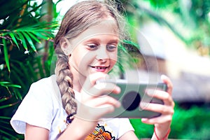 Technology and people concept - happy smiling girl using smartphone outdoors