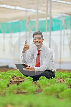 Technology and people concept, Young indian agronomist using tablet and showing thumps up at greenhouse