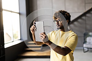 technology, people and lifestyle concept. Indian happy man with tablet standing in living room at home