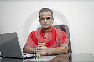 Technology, remote job and lifestyle concept - happy indian man in glasses with laptop computer sitting and looking at camera