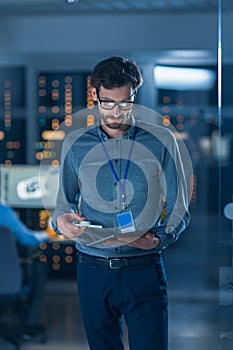 In Technology Research Facility: Chief Engineer Stands in the Middle of the Lab and Uses Tablet