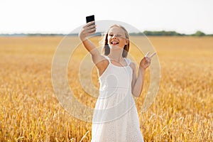 Girl taking selfie by smartphone and showing peace