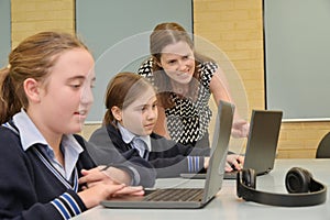 Technology teacher helping how to use laptops in classroom