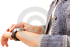 Technology, time, fast life. Woman in denim jacket looking at her wrist watch