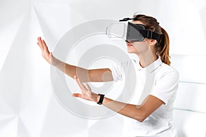 Technology, virtual reality, entertainment and people concept - happy young woman with virtual reality headset sits on a