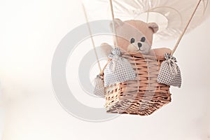 Teddy bear in a aerostatic balloon toy hanging from the ceiling.