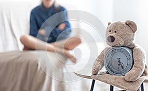 Teddy bear with alarm clock on a blurred background of the children`s room