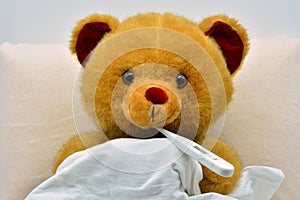 Teddy bear in bed, sick with fever photo
