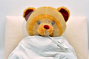Teddy bear in bed, sick with fever photo