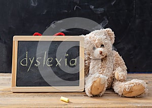 Teddy bear and a blackboard. Dyslexia text drawing on the blackboard photo