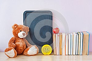 Teddy bear, blackboard and many textbooks. Back to school concept