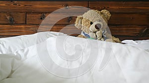 teddy bear in blue shirt on a bed