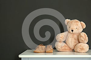 Teddy bear with bootees for baby room interior on table