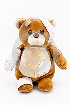 Teddy bear, bruised plush toy with bandages, childhood endangered conceptual image, domestic violence or child abuse