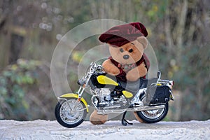 Teddy Bear with cap stands behind a motorcycle