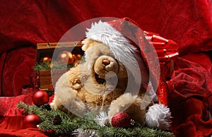 A teddy bear in a Christmas hat on red silk