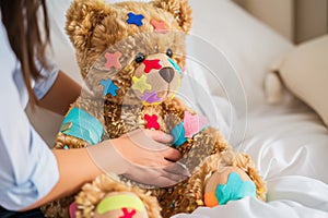 teddy bear with colorful bandaids and a person comforting it photo