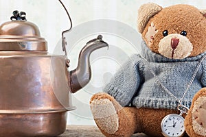 Teddy bear and copper kettle on background of old wallpaper
