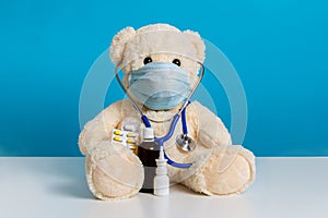 Teddy bear doctor with medical mask, stethoscope and medicine. Concept of hygiene and virus protection for child patient