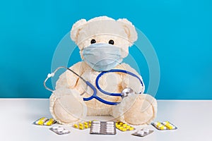 Teddy bear doctor with medical mask, stethoscope and pills. Concept of illness, hygiene and virus protection