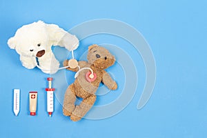 Teddy bear doctor with stethoscope and teddy bear patient on light blue background with wooden toy medicine tools